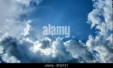 Dramatic Cloud Formation with Sunlight Breaking Through Against a Blue Sky Stock Photo