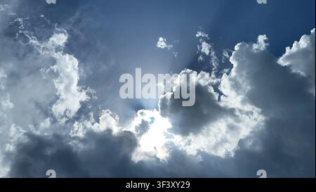 Dramatic Cloud Formation with Sunlight Breaking Through Against a Blue Sky Stock Photo