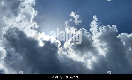 Dramatic Cloud Formation with Sunlight Breaking Through Against a Blue Sky Stock Photo