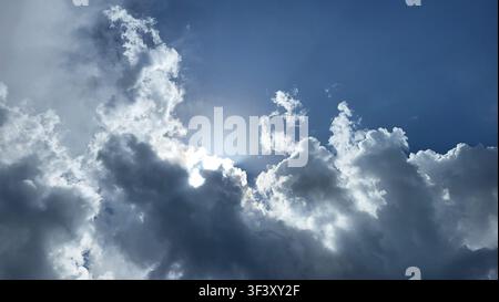 Dramatic Cloud Formation with Sunlight Breaking Through Against a Blue Sky Stock Photo