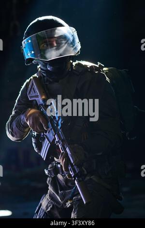 Tactical Soldier With Rifle and Visor Helmet in Low-Light Urban Military Operation and Combat Ready Stock Photo