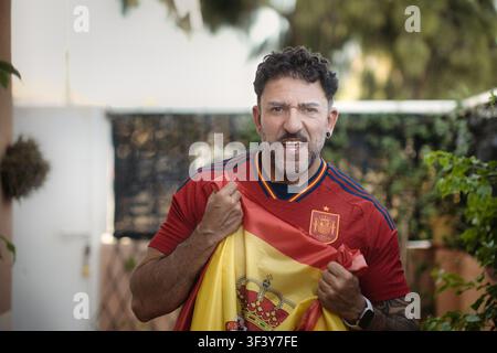 Excited Spanish soccer supporter cheering with emotional intensity outdoors Stock Photo