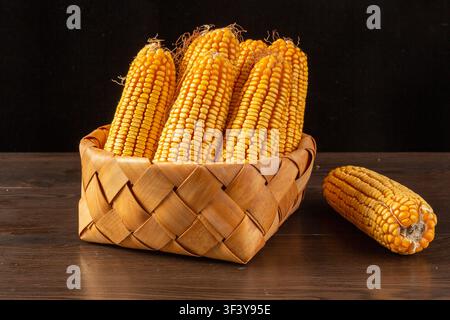 Dried yellow corn cobs arranged in a woven basket Stock Photo