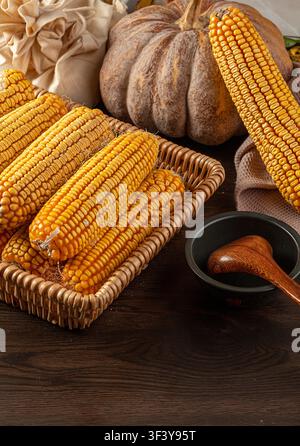Dried yellow corn cobs arranged in a woven basket Stock Photo