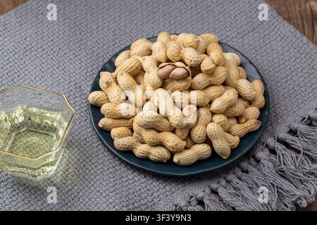 Roasted peanuts in shell served on blue dish Stock Photo