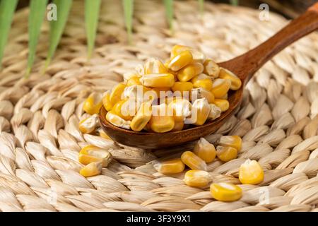 Yellow corn kernels served in a bowl with wooden spoon Stock Photo
