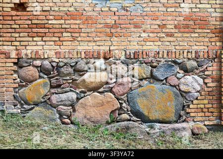 Abandoned Indura Synagogue wall features unique combination of weathered red clay bricks and massive stone boulders embedded in mortar, reflecting his Stock Photo