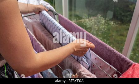 Woman Hanging Fresh Laundry on Balcony Drying Rack Stock Photo