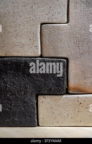 Close-up of textured ceramic tiles in staggered brick pattern, black beige and gray speckled glaze, minimalist wall design Stock Photo