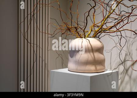 Minimalist Ceramic Vase with Twisted Decorative Branches on White Pedestal in Modern Interior Stock Photo