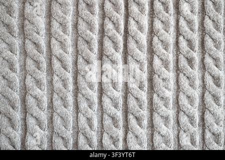 Cozy gray cable knit sweater fabric close-up showing textured pattern for winter and fashion Stock Photo