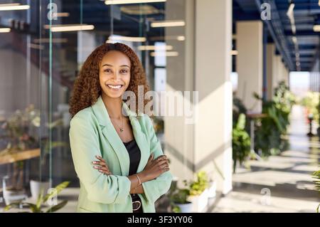 Professional manager in green blazer standing confident and smiling in office Stock Photo
