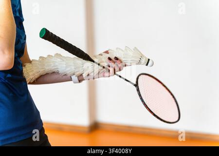 badminton coach holding feather shuttlecock stack and racket indoors Stock Photo