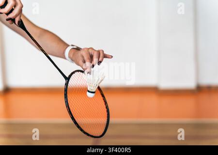 woman serving with feather shuttlecock on indoor badminton court Stock Photo