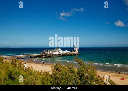 A seaside pier juts out into a deep blue sea beneath an almost cloudless blue sky, Bournemouth, Dorset, England. Stock Photo