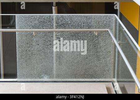 Shattered tempered glass balcony railing panel with fine crack pattern and stainless steel handrail in modern building in Monaco. Stock Photo