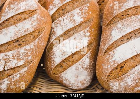 Freshly baked artisanal rye bread loaves displayed in a wicker basket at a market in Arles, France. Stock Photo