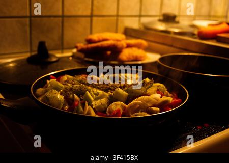 Chopped vegetables in a frying pan on a kitchen stove. Stock Photo