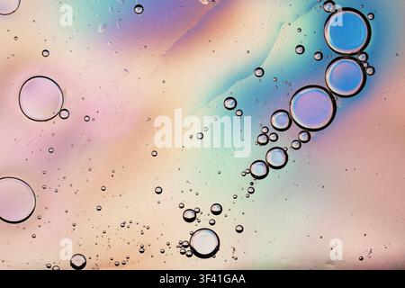 Oil drops creating an abstract colorful iridescent pastel background texture in water Stock Photo