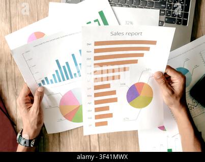 Person holds business reports with colorful charts and graphs. Hands show data analysis or financial review. Image fits business, finance, or marketin Stock Photo