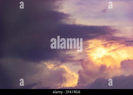 A horizontal background photograph capturing dense, dramatic cumulonimbus clouds glowing with bright golden and orange sunlight during sunset against Stock Photo