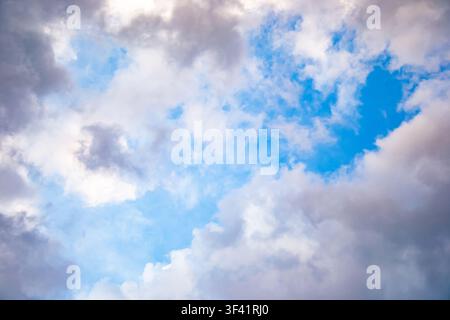 A horizontal photograph captures dense white and soft grey clouds filling a vibrant blue sky under bright natural daytime light, creating a textured a Stock Photo
