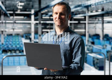 Portrait of smiling data center technician analyzing system performance, reducing downtime and preventing equipment failures. Happy server hub worker automating anomaly detection Stock Photo