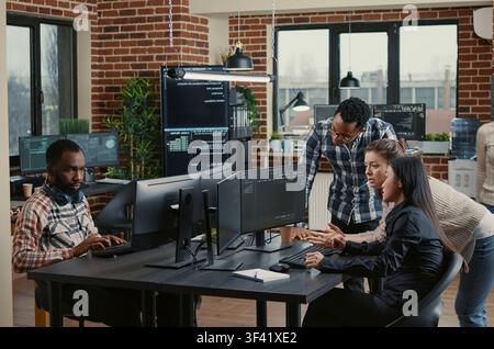 Junior programmers collaborating on software project compilation in a programming workspace, connecting source code, database logic and collaborative development for a technology project. Stock Photo