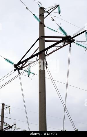 High-voltage power lines. Top of a concrete power line pole with rusty metal cross bars and glass pin insulators. Industrial landscape. Stock Photo