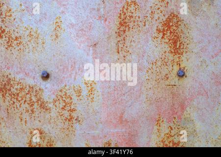 Texture of a rusty metal plate painted with old pink paint. Weathered iron surface and the background are made of vintage corroded material. Oxidized Stock Photo