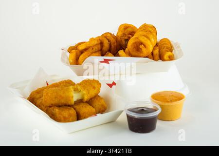 Crispy mozzarella sticks and golden curly fries with dipping sauces on white Stock Photo