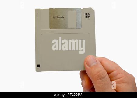 A human hand holding a vintage 3.5-inch floppy disk isolated on a white background, retro computer data storage technology Stock Photo