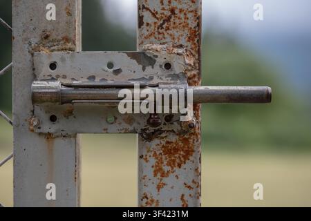 Rusty metal gate latch closing preventing entry, showing weathered texture Stock Photo
