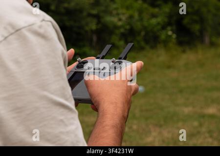 Person operating a drone controller with hands, enjoying a hobby outdoors Stock Photo