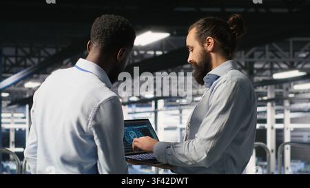 Data center workers cooperating, doing maintenance on rigs handling AI processing tasks. Server hub admins doing brainstorming, managing storage arrays supporting deep learning technology Stock Photo