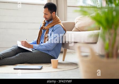 Focused Young Black Man Writing Notes On Notebook At Home, Relaxing Lifestyle Stock Photo