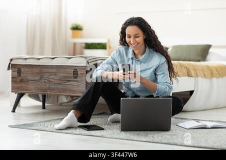 Happy Young Woman Using Smartphone And Laptop At Home, Study Concept Stock Photo