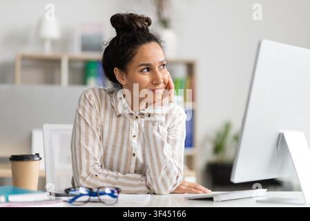 Thoughtful Young Hispanic Woman Working At Desk In Office, Business Concept Stock Photo