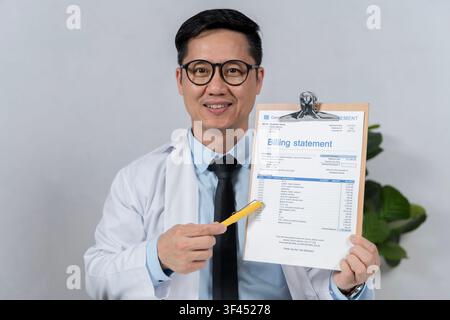 Smiling doctor pointing to a billing statement on a clipboard, illustrating healthcare costs, insurance claims, hospital administration, patient commu Stock Photo