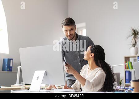 Business Meeting Between Hispanic Male And Female Colleagues In Office, Collaborating And Discussing Stock Photo