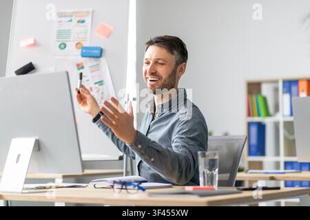 Smiling Caucasian Man Presenting Ideas At Desk In Office, Business Concept Stock Photo