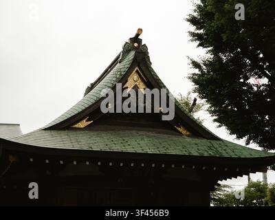 Curved gable roof of a traditional Shinto shrine with gold ornaments and green shingles in Daizawa, Setagaya, Tokyo, Japan Stock Photo