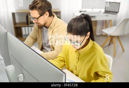 Focused female analyst working on spreadsheets at desktop monitors in office Stock Photo