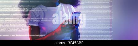 Focused Black Female Using Smartphone With Coding Text Overlaid, Tech Concept Stock Photo