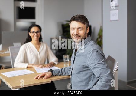 Smiling Male And Female Professionals Collaborating At Office Desk, Business Concept Stock Photo