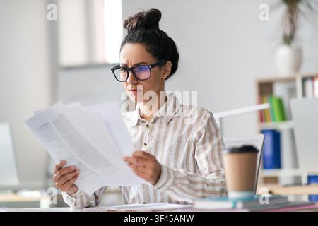 Focused Hispanic Woman Analyzing Documents At Office, Business Concept Stock Photo