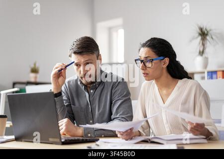 Worried Young Caucasian Man And Woman Analyzing Documents Together At Office, Business Concept Stock Photo