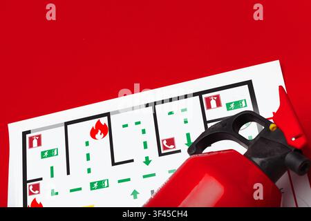 Emergency 911 plan with fire extinguisher and escape route map on red background in office setting Stock Photo