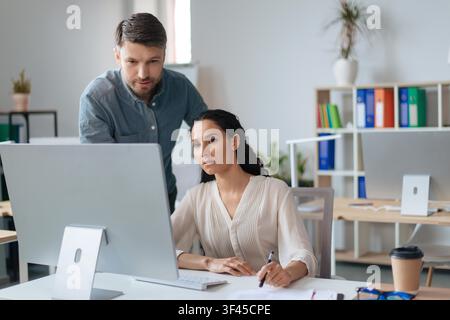 Business Professionals Collaborating In Office, Focused On Computer Screen Stock Photo