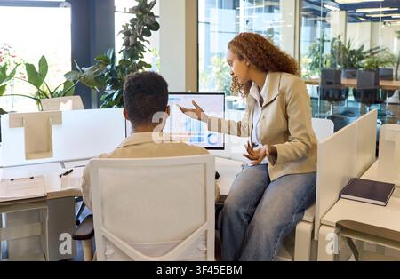 Financial analysts discussing data charts on computer in office meeting team Stock Photo